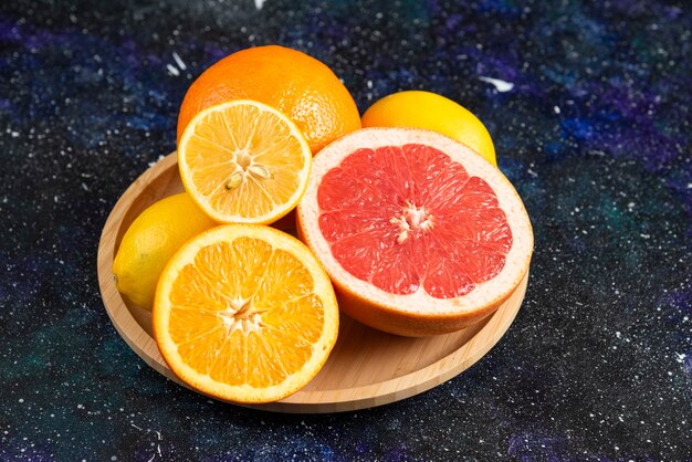 Fresh half cut citrus fruits on wooden plate. 