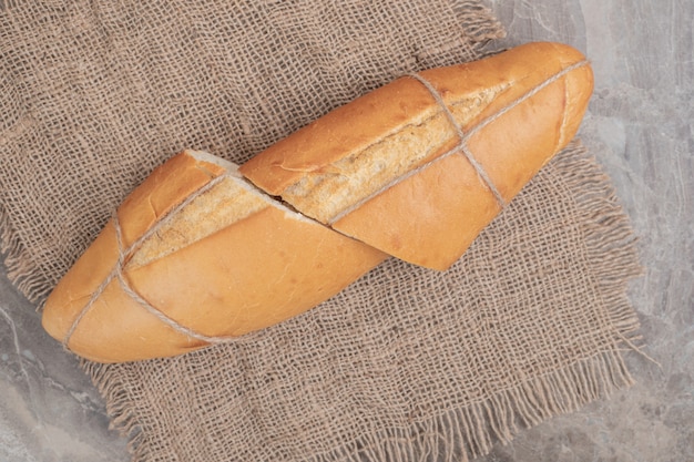 黄麻布にロープで結んだ焼きたてのパンのハーフカット。高品質の写真