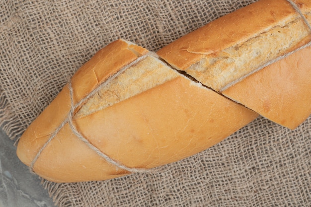 Fresh half cuts of bread tied with rope on burlap. High quality photo