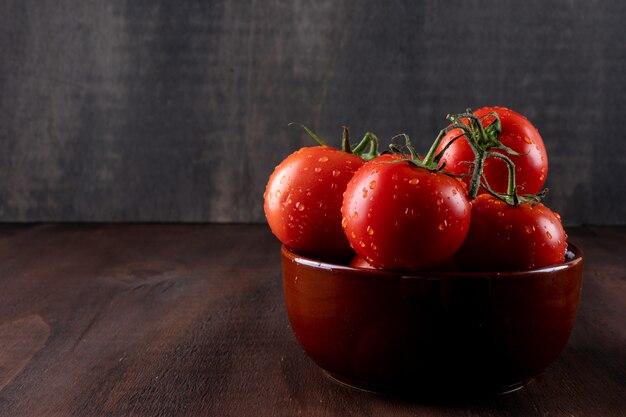 Fresh and health tomatoes in ceramic bowl on brown stone surface