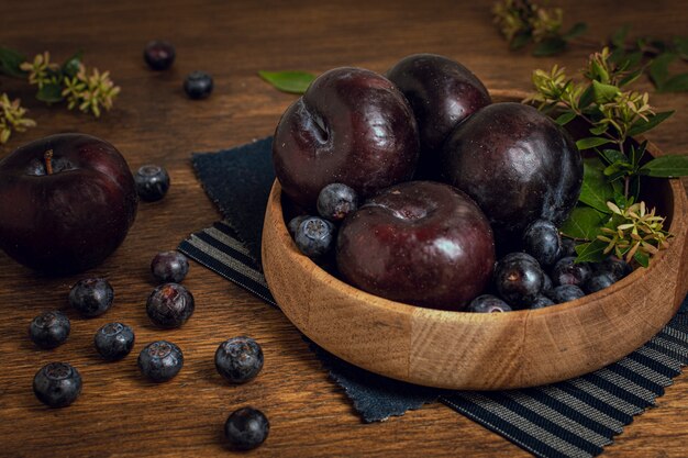 Fresh healthy bowl full of plums and blueberries