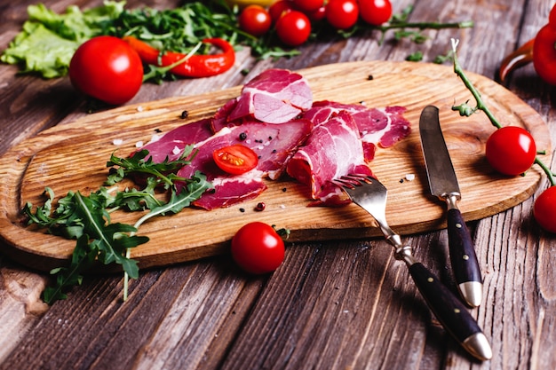Свежая и полезная еда. Нарезанное красное мясо лежит на деревянном столе с рукколой
