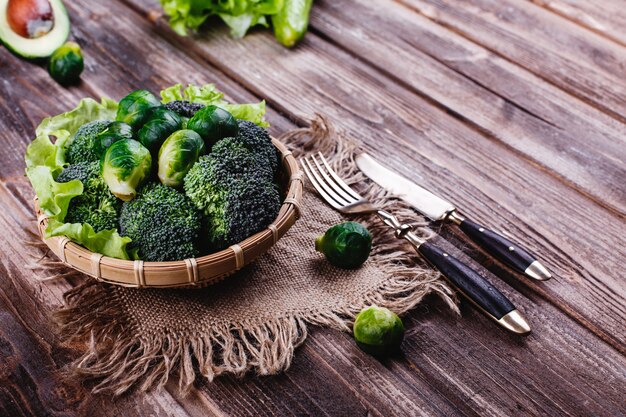 Fresh and healthy food. Wooden bowl with broccoli, brussel sprouts, olive oil, green pepper