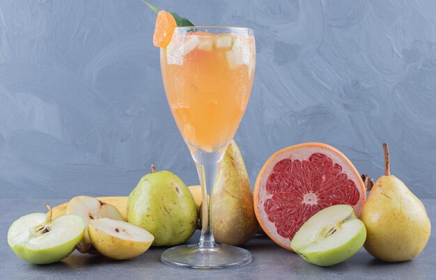 Свежий здоровый фруктовый сок на сером фоне с сезонными фруктами.