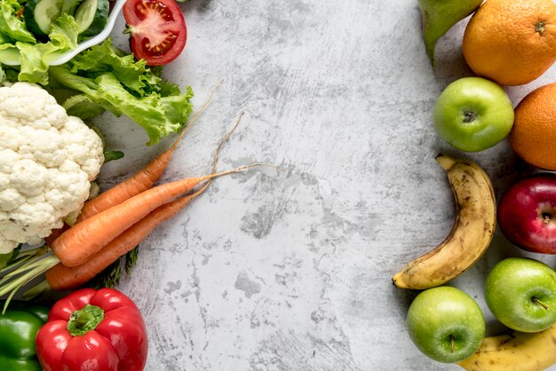 Fresh healthy vegetables and fruits over concrete backdrop