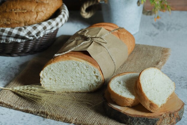 Fresh homemade bread tied with rope on stone surface.