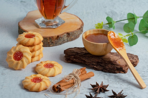 Fresh homemade cookies with jam and tea on grey wall.