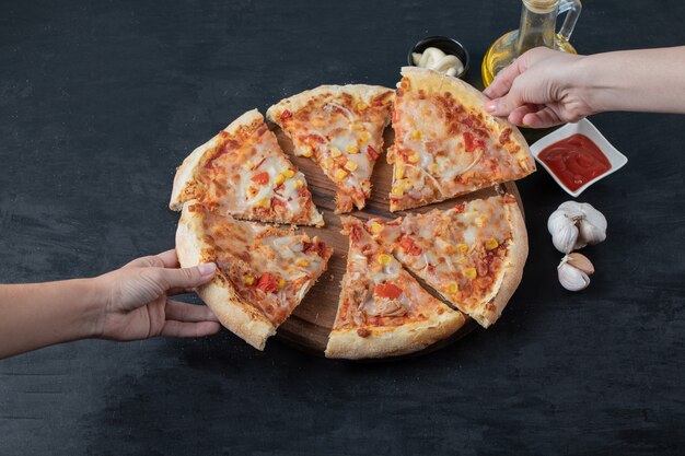 Fresh homemade delicious pizza. Female hand taking pizza slice. Wide angle. 