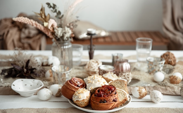 Свежая домашняя пасхальная выпечка на праздничном столе с деталями декора на размытом фоне.