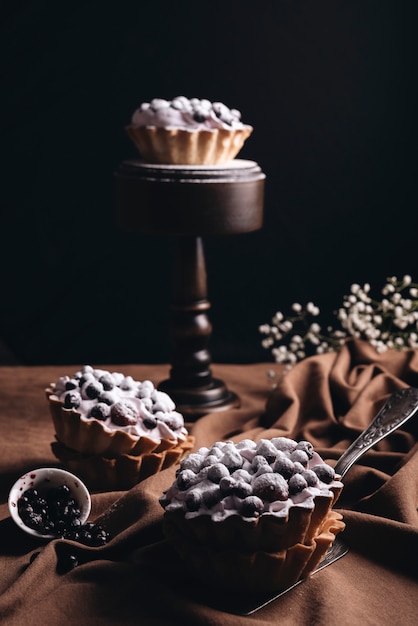 Fresh homemade fruit tart on brown tablecloth against black backdrop