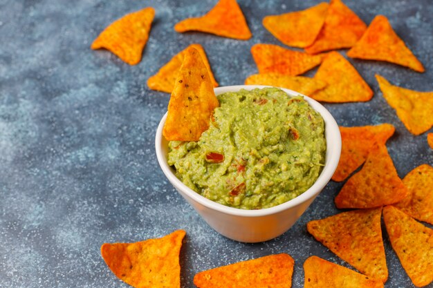 Fresh homemade hot guacamole sauce with nachos, top view