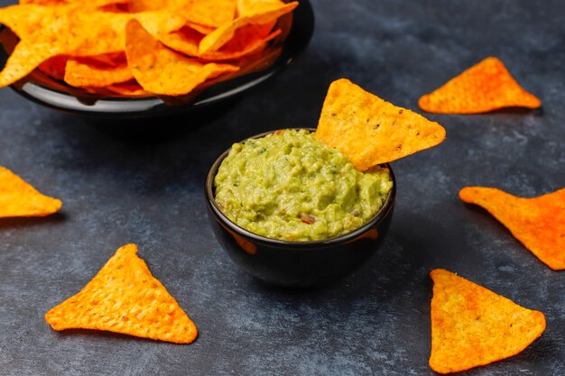 Fresh homemade hot guacamole sauce with nachos, top view