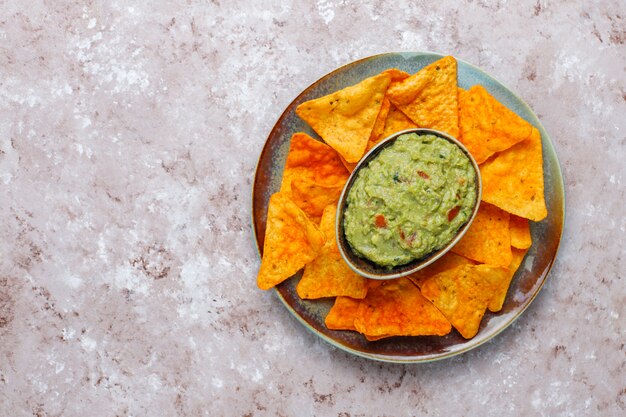 Fresh homemade hot guacamole sauce with nachos, top view