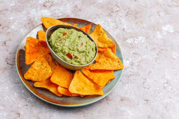 Fresh homemade hot guacamole sauce with nachos, top view