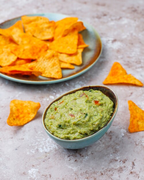 Fresh homemade hot guacamole sauce with nachos, top view