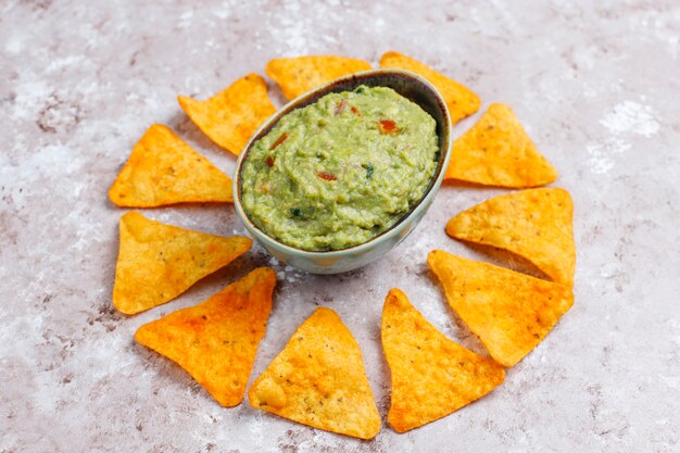 Fresh homemade hot guacamole sauce with nachos, top view