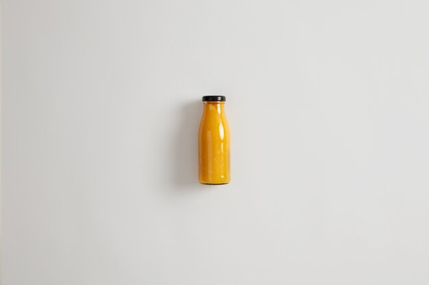 Fresh homemade mango pineapple orange smoothie in glass bottle isolated on white background. Balanced combination of carbs, fiber, protein and healthy fats. Beverage that maintains calorie deficit