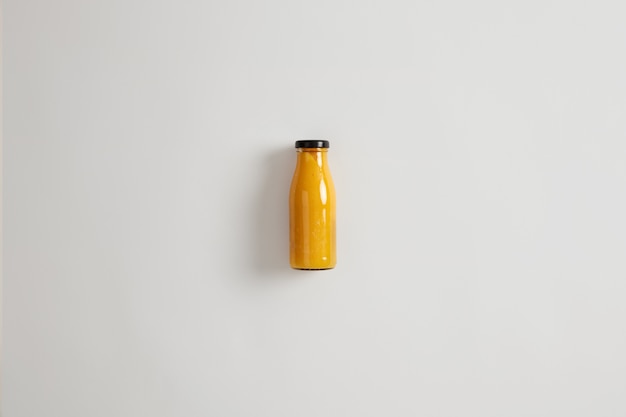 Fresh homemade mango pineapple orange smoothie in glass bottle isolated on white background. Balanced combination of carbs, fiber, protein and healthy fats. Beverage that maintains calorie deficit
