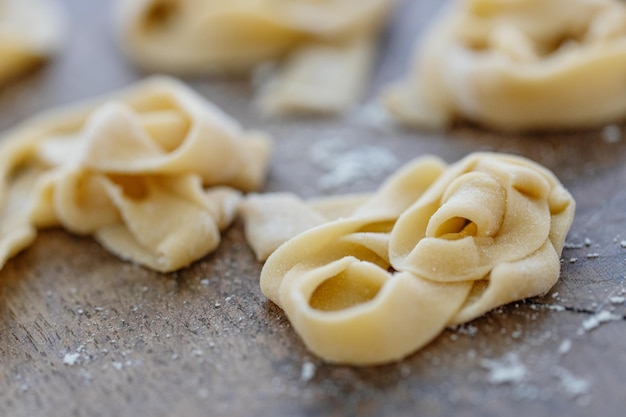 Fresh homemade pasta with flour on wooden board on table.