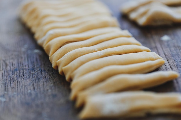 Fresh homemade pasta with flour on wooden board on table.