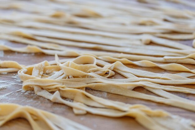 Fresh homemade pasta with flour on wooden board on table.