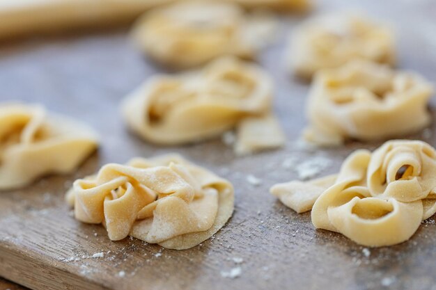 Fresh homemade pasta with flour on wooden board on table.