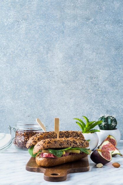 Fresh hot dogs on wooden board with jar of chilli flakes; potted plant fig slices and almonds