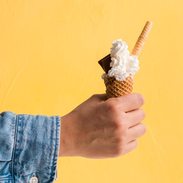 Fresh ice cream with chocolate in cone in hand