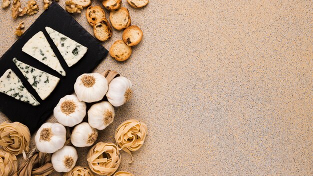 Fresh ingredients and gorgonzola cheese slices on slate tray over textured surface