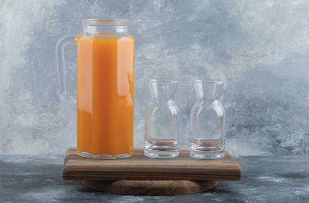 Fresh juice and empty glasses on wooden board. 