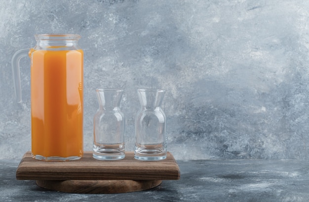 Fresh juice and empty glasses on wooden board. 