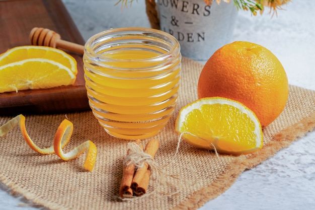 Fresh juice with orange slices on grey wall.