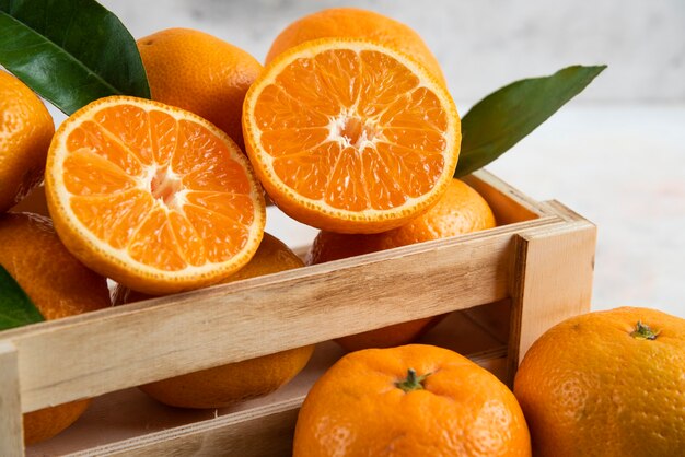 Fresh juicy Clementine in wooden box. Whole or half cut