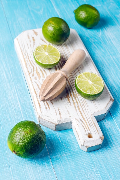 Free photo fresh key limes with wooden citrus juicer,top view