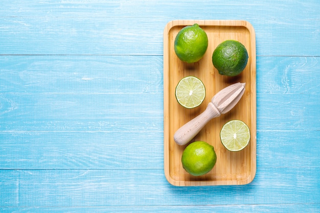 Free photo fresh key limes with wooden citrus juicer