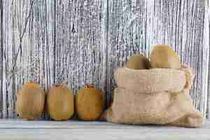 Free photo fresh kiwi in a sack on a wooden table. side view.