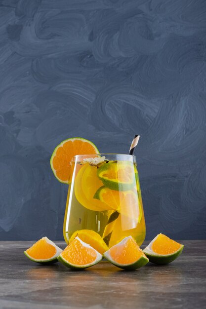 Fresh lemonade with lemon and straw on marble wall.