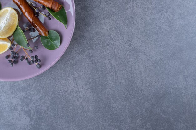 Fresh lemons slices on purple plate over grey background.