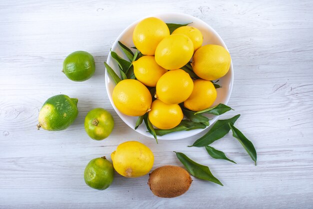 Fresh lemons with leaves top view on wood table