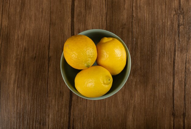 Fresh lemons in a yellow bowl. top view
