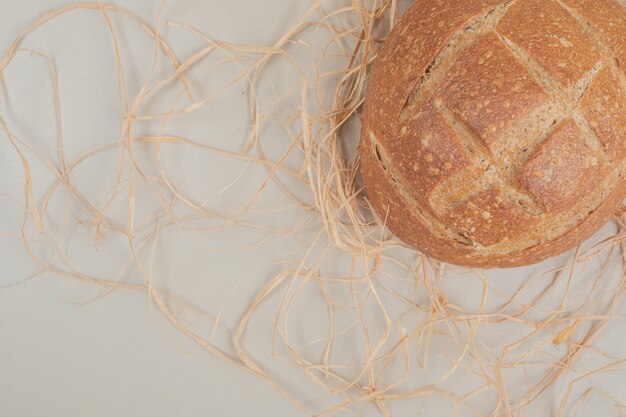 Fresh loaf of bread on white surface