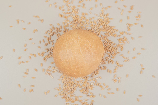 Fresh loaf of bread with grains on white surface