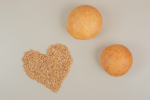 Fresh loaf of bread with oat grains on white surface