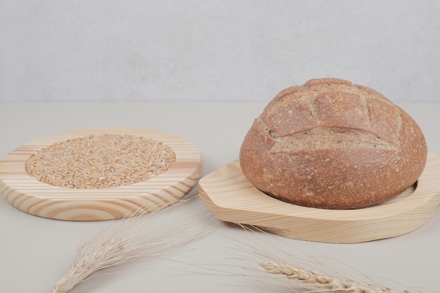 Fresh loaf of bread with wheat on wooden plate