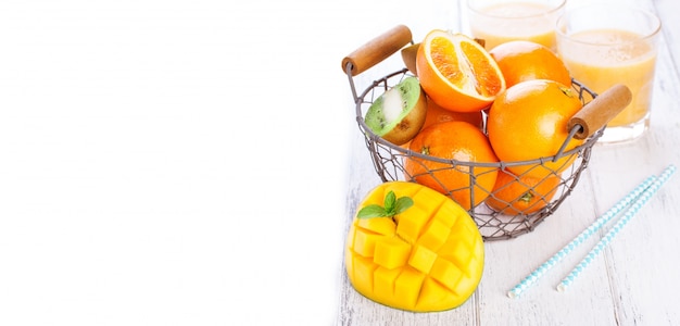 Fresh mango next to a basket with oranges