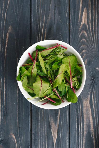 Fresh mangold or swiss chard in a white bowl on black wooden desk