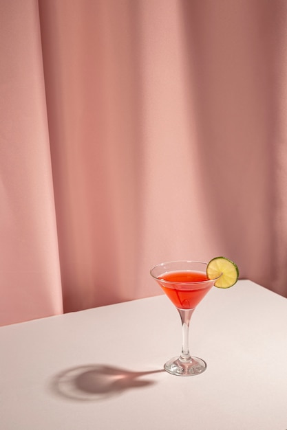 Fresh margarita cocktail drink with lemon slice on table against pink curtain