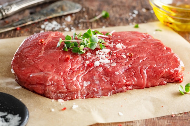 Fresh meat steak on old wooden board. Dark background. Closeup