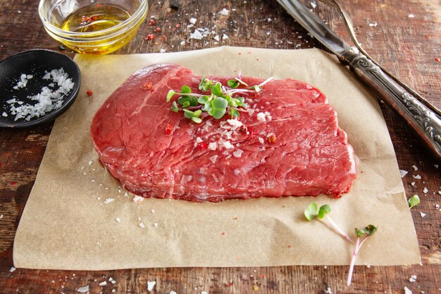 Fresh meat steak on old wooden board. Dark background. Closeup