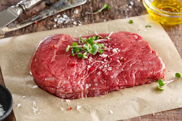 Fresh meat steak on old wooden board. Dark background. Closeup